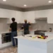 Kitchen remodeling scene residential kitchen under renovation workers installing cabinets construction in progress tools and materials partially completed kitchen new countertops being installed modern kit