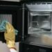 compressed woman yellow gloves cleaning oven