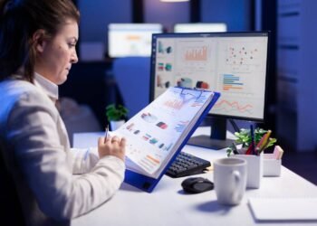 freelancer woman comparing graphics from clipboard with grafics from computer business office1