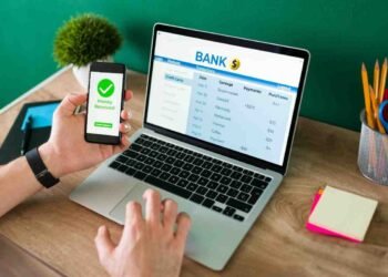 wire transfer young man using his smartphone laptop banking transaction some payments 1